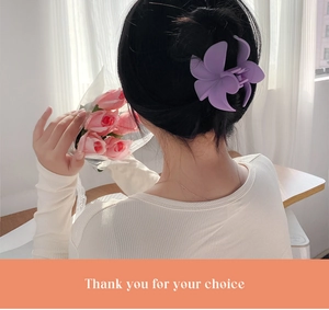 Detail view of a matte purple floral hair claw clip worn on a elegant hairstyle