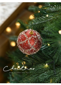 Close-up of a red 8cm Christmas ball with glitter dots hanging on a festive tree