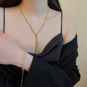 Detail of a multi-layer gold tassel necklace and bracelet set worn by a fashion model