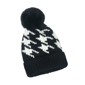 Classic black and white houndstooth knit beanie with a fluffy faux fur pompom for winter