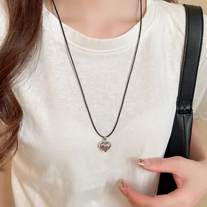 Minimalist heart pendant necklace with black wax cord shown on model wearing white shirt