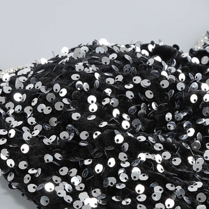 Macro shot of silver sequins stitched on black velvet fabric for elegant evening dresses