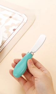 Dettaglio di un coltello da burro in acciaio inox con manico in ceramica blu in mano