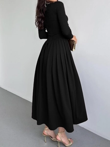 Détail d'une élégante robe longue noire à manches longues avec jupe plissée et tissu lisse
