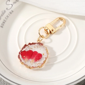 Detail of resin keychain with red rose petals, gold foil flakes and golden metal clasp