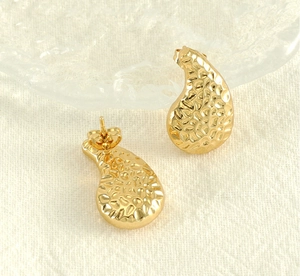 Détail de boucles d'oreilles goutte dorées avec texture martelée et fermoir papillon