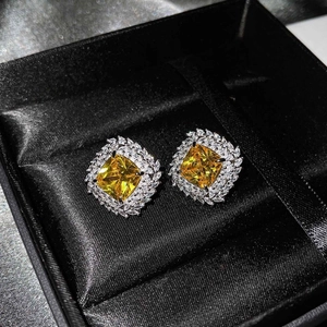 Close-up of luxury square yellow gemstone stud earrings in a premium black jewelry box
