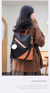 Detail of waterproof black backpack with brown leather trim and a white fur ball charm