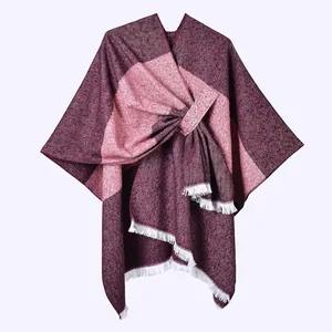 Detail view of the thick knit fabric texture and white fringe tassels on the poncho