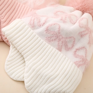 Pink and white knitted earflap hat for girls featuring bow jacquard and a faux fur pompom
