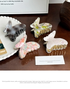Detail shot of acetate butterfly hair claws in floral and marble patterns on a wooden table