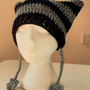 Detail of hand-knitted cat ear hat with black and grey stripes and star pendants