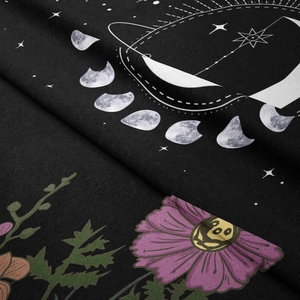 Macro shot of bohemian moon phase tapestry showing soft velvety texture and purple floral print
