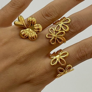 Polished 18k gold plated stainless steel flower rings shown on hand in a trio set