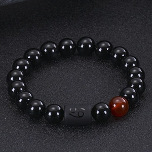 Detail of black onyx bracelet with red bead and Cancer zodiac sign bead charm