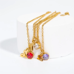Gold stainless steel zodiac necklace with colorful gemstone pendants on white pedestal