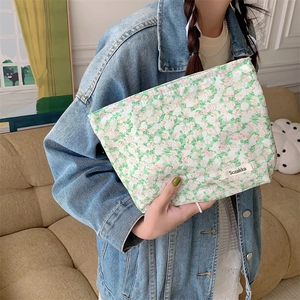 Model holding a green and pink floral cotton pouch bag in a cozy indoor setting
