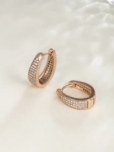 Macro detail of rose gold hoop earrings with pavé set zircon stones in U-shape design