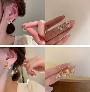 Detailed view of gold flower earrings with pearls and butterfly design details