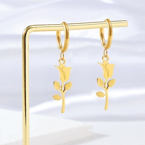 Polished gold stainless steel rose flower drop earrings displayed on a golden metal stand