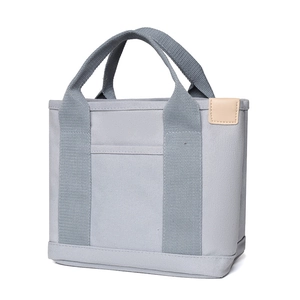 Close-up of grey canvas lunch tote bag with beige leather patch and fabric handle