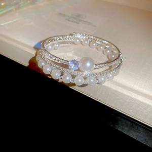 Close-up of layered pearl and crystal bangle with large central rhinestone detail
