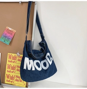 Detail of blue denim tote bag featuring large white MOOD lettering and retro wash finish