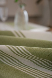 Detailed texture of green striped linen tablecloth with soft natural fabric draping