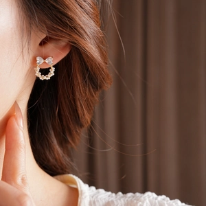Détail d'une boucle d'oreille nœud et perle avec zircons portée par un mannequin