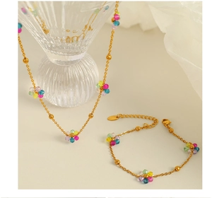 Artistic close-up of handmade golden necklace and bracelet set with colorful bead flowers
