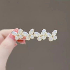 Close-up of four butterfly hair clips in light gold with aurora white opal petals