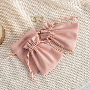 Detail view of two light pink velvet drawstring pouches on a neutral grid background