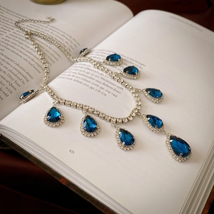 Retro vintage necklace with water-drop blue gemstones displayed on an old book
