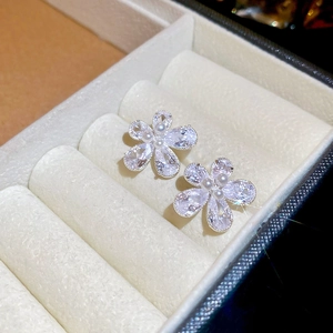 Macro view of silver flower stud earrings with sparkling zircon petals and pearl center