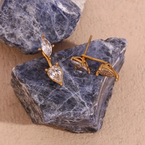 Close-up of 18K gold earrings with marquise and pear cut zircon on blue stone