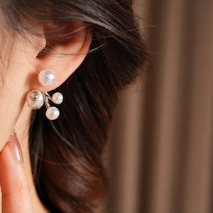 Close-up of pearl cluster earrings on a model showing elegant white pearls and silver posts