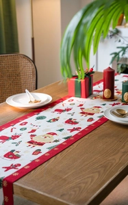 Detail of Christmas table runner with reindeer and Santa motifs on a wooden table