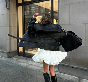 Détail d'une jupe plissée blanche à taille haute avec une veste en cuir noir