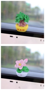 Close-up of cute lucky money tree and lotus car ornaments on a central console dashboard
