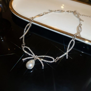 Elegant silver bow necklace with sparkling crystals and a large drop pearl pendant