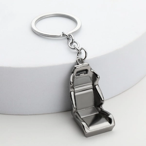 Detailed view of a metal car seat keychain in dark grey finish on a white stand
