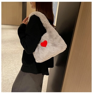 Detailed texture of gray plush shoulder bag featuring a red heart patch and soft faux fur