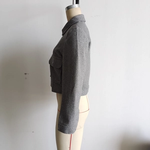 Détail de la veste courte en tweed gris montrant le col à revers et les poches
