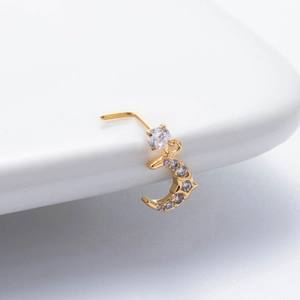 Macro d'un piercing de nez en or en L avec un pendentif lune orné de zircons