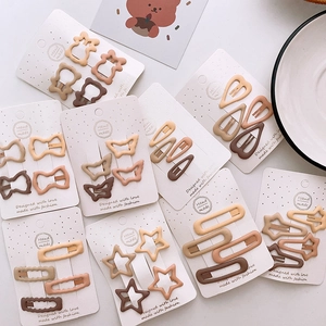 Detail of matte earth-toned hair clips in butterfly, heart and star shapes on white cards