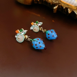 Macro shot of blue strawberry drop earrings with colorful beads and gold metal pins