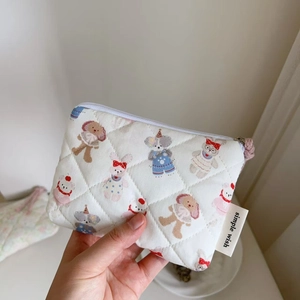 Detailed macro view of quilted floral cotton pouch with cartoon animal motifs and side tag