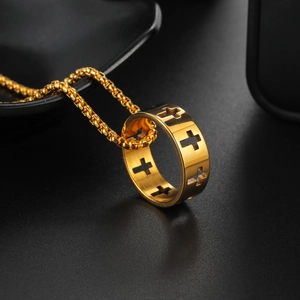 Goldene Edelstahlkette mit ausgehöhltem Kreuzring-Anhänger auf schwarzem Teller
