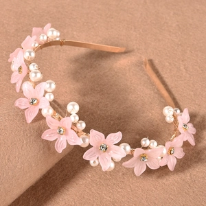 Detail of gold metal headband with pink resin flowers, pearls, and crystals on felt