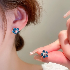 Sweet floral stud earrings featuring deep blue petals and a pink rhinestone center